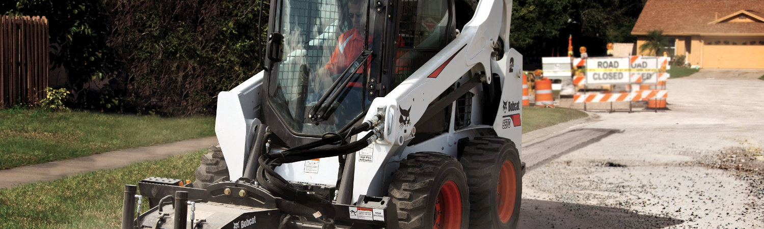 2018 Bobcat® S570 on a street next to a side walk and grass with road closed signs in the background